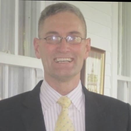 Smiling man in suit and glasses.