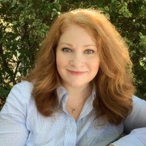 Woman with red hair smiling outside.