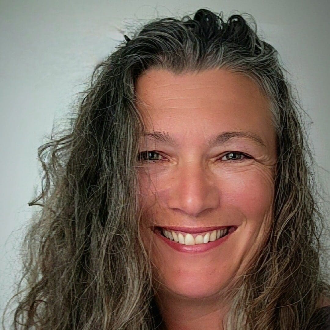 Smiling woman with long gray hair.