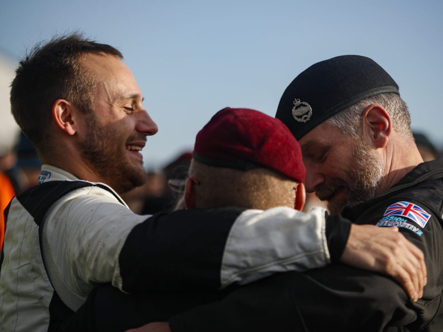 Three men embracing with smiles.