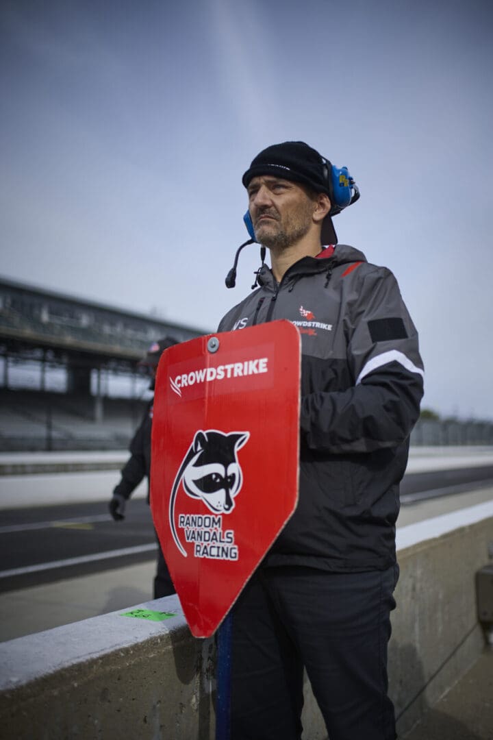 Man holding Crowdstrike sign with raccoon logo.