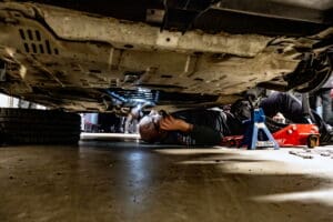 Mechanic working under a car with a flashlight.