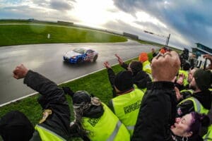 Race car driver cheered on by crowd.