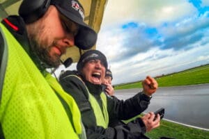 Three men watching a race track.