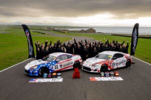 Team photo with race cars and crew.