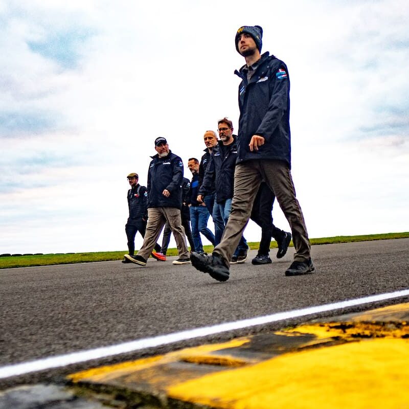 Men in jackets walking on a track.