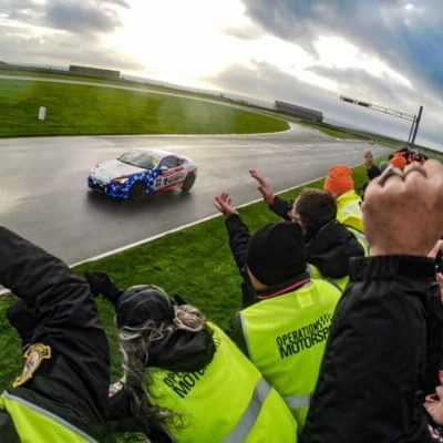 Race car on track with cheering fans.